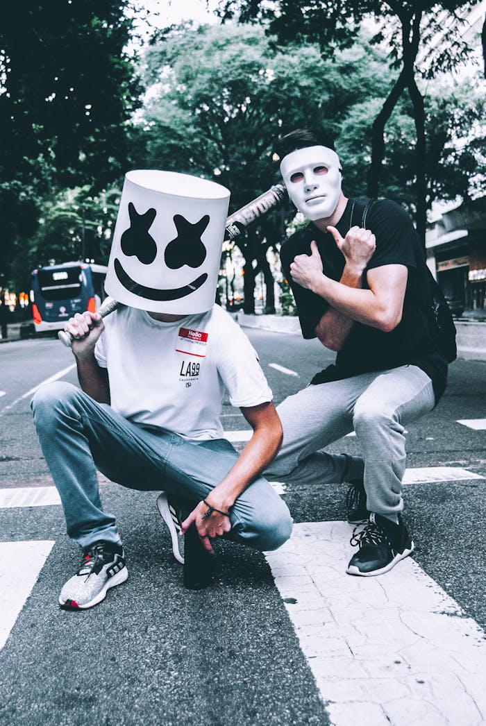 Two masked individuals squatting on a pedestrian crossing, urban street scene.
