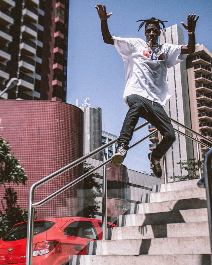 Energetic man in streetwear jumps on city stairs, showcasing urban lifestyle.